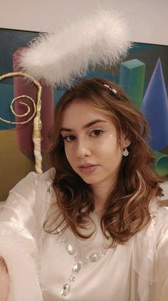 a woman in a white dress with a feather hat on top of her head, looking at the camera