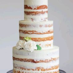 a three tiered cake with white and orange frosting on a silver platter