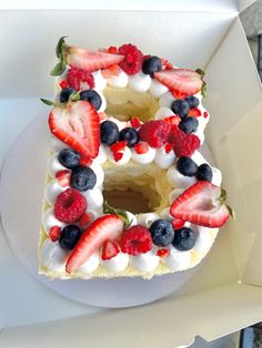 a cake with berries and whipped cream in the shape of the letter e