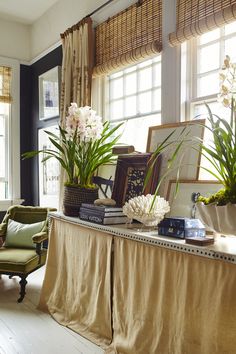 a living room filled with lots of furniture and flowers on top of a table next to a window