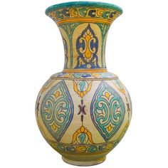 an ornate vase with blue, yellow and green designs on it's sides against a white background