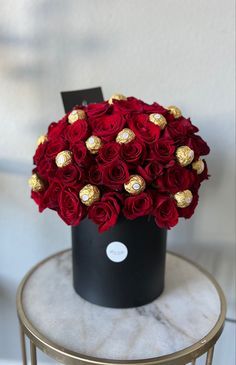 a black box with red roses and chocolates in it sitting on a small table