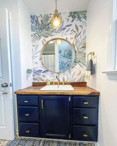 a bathroom with blue cabinets and a mirror on the wall above it, along with a rug