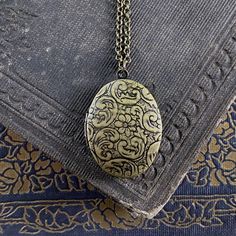 Oval vintage style locket. It is antiqued brass and the inside is quite a bit darker. On 28 inches of antiqued brass chain. Vintage Etched Oval Pendant Locket Necklace, Ornate Bronze Locket Necklace With Antique Finish, Vintage Brass Locket Necklace With Oval Pendant, Vintage Charm Oval Pendant Locket Necklace In Brass, Vintage Oval Pendant Necklace With Antique Finish, Ornate Bronze Locket Necklace In Brass, Ornate Antique Gold Brass Locket Necklace, Antique Gold Oval Pendant Locket Necklace, Ornate Bronze Brass Locket Necklace