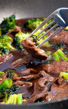 the beef and broccoli is being cooked in a skillet with a fork