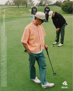 a man standing on top of a green field holding a golf club