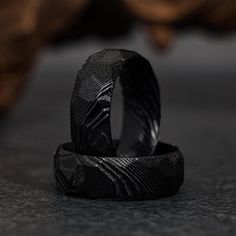 two black wedding bands sitting on top of each other