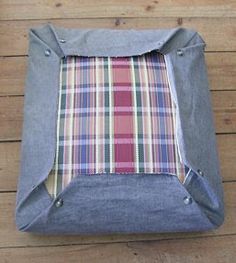 a piece of cloth sitting on top of a wooden floor next to a bag with plaid lining