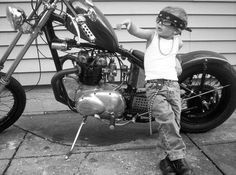 a little boy standing next to a parked motorcycle