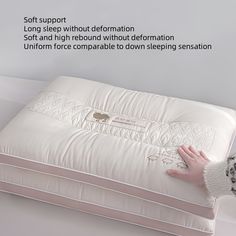 a woman's hand is touching the bottom of a white pillow on a bed