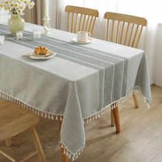 a dining room table with two chairs and a white vase filled with flowers on it