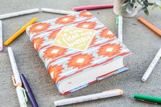 an open notebook sitting on the ground surrounded by crayons and markers