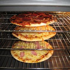 three pizzas cooking in an oven on racks