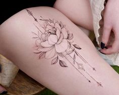 a woman's thigh with a flower and arrow tattoo on her left side leg