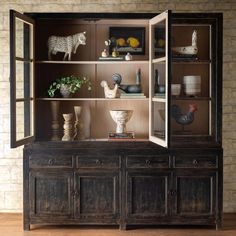 an old wooden cabinet with many items on it's shelves, including figurines and vases