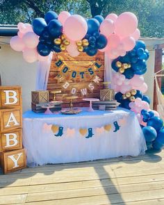 a baby shower table with blue and pink balloons