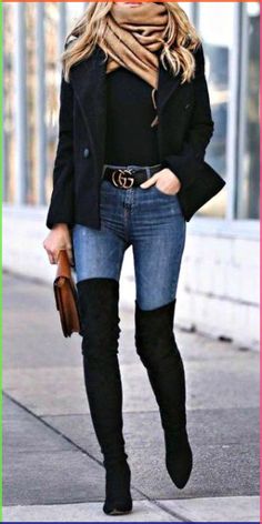 a woman in black jacket and jeans walking down the street with her hand on her hip