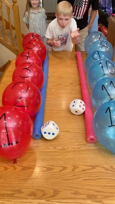 two boys and one girl standing in front of a table with balloons that spell out numbers