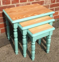 three wooden tables sitting next to each other on top of a cement ground in front of a brick wall