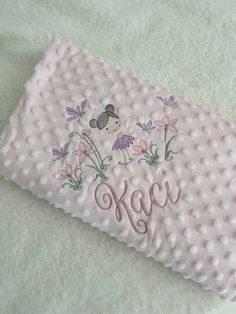 a white towel with pink flowers and a koala embroidered on the front is laying on a bed