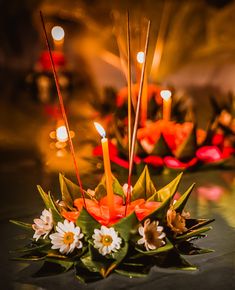 candles are lit on top of flowers and leaves in front of some other decorative objects