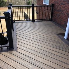 a wooden deck with black railings next to a brick building