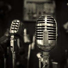 an old fashioned microphone is sitting in front of two other vintage microphones, one black and white