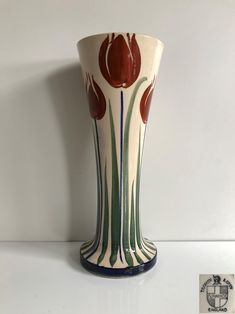 a white vase with red and green flowers on it