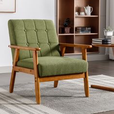 a green chair sitting on top of a rug next to a wooden table and bookshelf