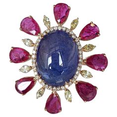 A very gorgeous, one of a kind and modern, Tanzanite & Ruby Cocktail Ring set in 18K Rose Gold & Diamonds. The weight of the Tanzanite Cabochon is 15.48 carats. The Tanzanite is responsibly sourced from Tanzania. The weigh of the pear shaped Rubies is 5.85 carats. The Rubies are completely natural, without any treatment and is of Mozambique origin. The weight of the yellow Marquise Diamonds is 0.66 carats. Other Diamonds weight is 0.31 carats. Net 18K Gold weight is 8.14 grams. The gross weight Ruby Cocktail, Fancy Jewelry Necklace, Diamond Cocktail Rings, Fancy Jewelry, Marquise Diamond, Ruby Diamond, Sapphire Jewelry, Rose Gold Diamonds, Natural Ruby