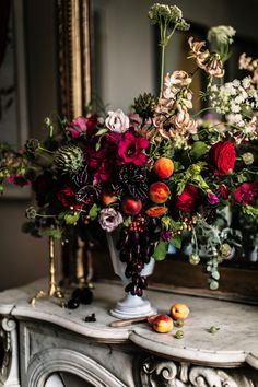 a vase filled with lots of flowers sitting on top of a table next to a mirror