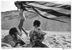 two women sitting on the beach with an american flag in the background