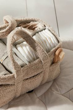 a pile of folded towels sitting on top of a white bed next to a wooden brush