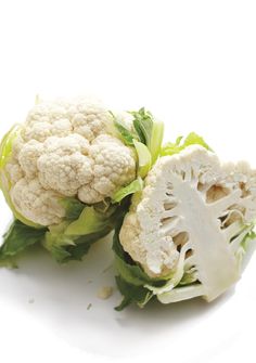 cauliflower is cut in half on a white surface