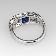 This lovely circa 1930s antique sapphire ring is centered with one (1), bead set, oval cut natural blue sapphire weighing 0.81 carats and flanked to each side by one (1), bead set, old European cut diamond. The shoulders of the ring are each bead set with two (2) round single cut diamonds. The gemstones are bordered with milgrain edging. Engraved details accent the side faces of the ring. The ring measures 7.3mm at the top, rises 3.7mm above the finger, tapering to 2.9mm wide and 1.6mm thick at the base of the shank. The ring is currently a size 6 and we offer complimentary resizing to fit. Classic Oval Sapphire Ring, Classic Oval Cabochon Sapphire Ring With Bezel Setting, Classic Sapphire Ring With Oval Cabochon Bezel Setting, Classic Sapphire Ring Oval Cabochon, Classic Sapphire Birthstone Ring, Classic Sapphire Halo Ring, Classic Sapphire Ring In 14k White Gold, Blue Oval Sapphire Ring In Art Deco Style, Elegant Sapphire Signet Ring