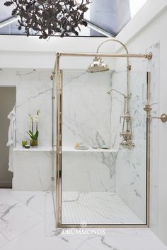 a bathroom with marble walls and flooring is shown in this image, it has a large glass shower door