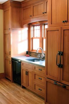 an empty kitchen with wooden cabinets and black dishwasher on the counter top,