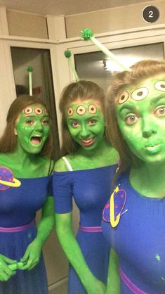 three women dressed in green and blue posing for the camera with their faces painted like aliens