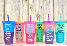 six different colored tumblers with straws in them sitting next to each other on a wooden table