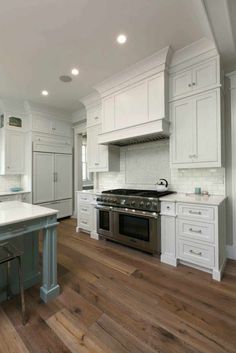 a kitchen with white cabinets and an island in the middle is shown, along with hardwood flooring