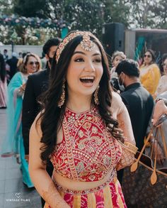 a woman in a red and yellow outfit is smiling at the camera with other people around her