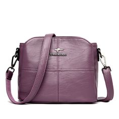 a purple cross body bag sitting on top of a white table