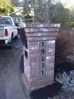 a brick mailbox sitting on the side of a road next to a white truck