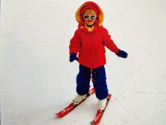 a young child wearing skis on a snow covered slope with goggles and a red jacket