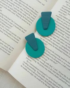 two bookmarks sitting on top of an open book next to each other in front of a page