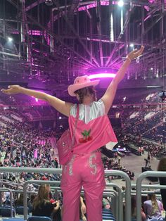 a woman in pink is standing on the bleachers with her arms spread out