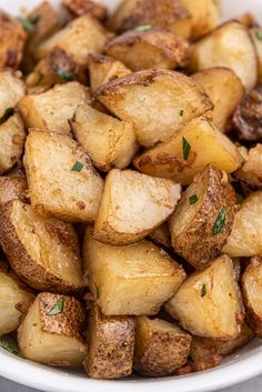 a white bowl filled with cooked potatoes on top of a table