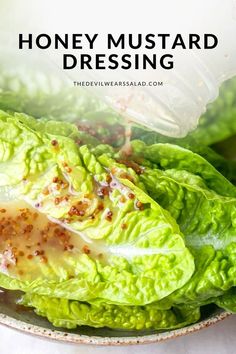 lettuce in a bowl with dressing being drizzled over it and the words honey mustard dressing on top