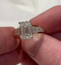 a person holding an engagement ring with a baguette cut diamond in the middle