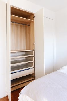 an empty bed in a room with white walls and wood flooring on the side